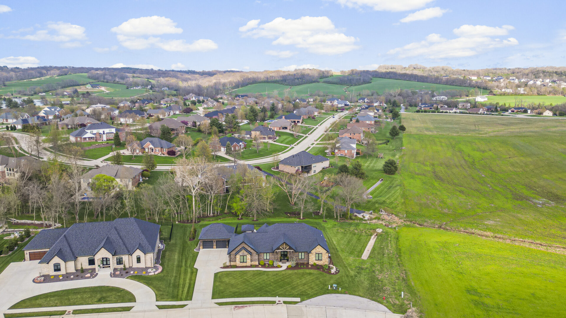 drone A contemporary mountain-style home features a stone and brick exterior. Over the front entrance, dark wooden beams stretch out, adding a touch of grandeur.