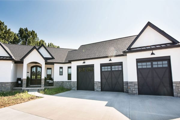 Modern farmhouse-style ranch boasting a striking black and white exterior, complemented by white painted bricks and elegant black wooden panel doors. pioneer ridge