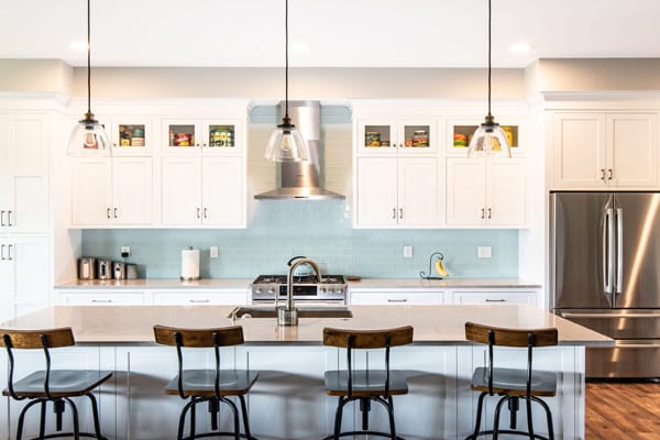 A stunning modern kitchen featuring custom white cabinets and a blue glass backsplash.