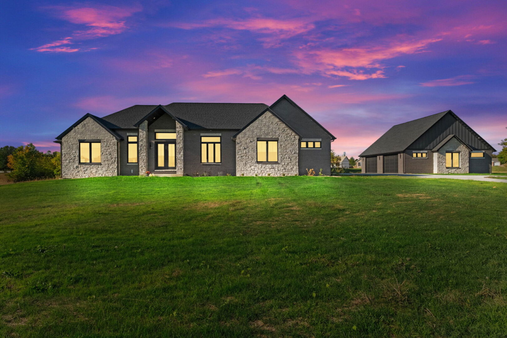 Twilight A contemporary-style home featuring black brick and stone, complete with an additional detached garage.