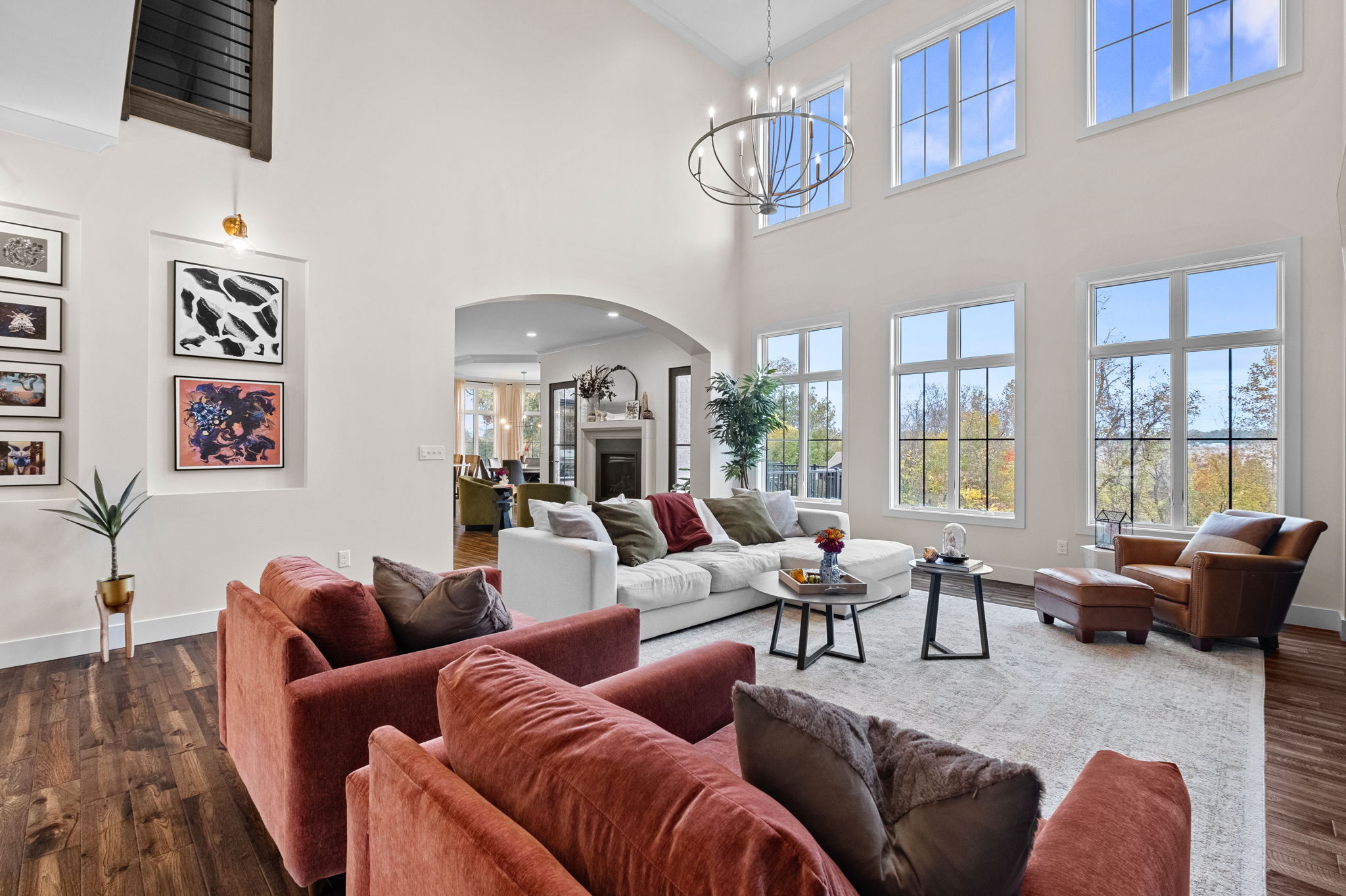 The Great Room boasts over 14-foot ceilings and a wall of windows that flood the space with natural light, complemented by a beautifully detailed arch entry.