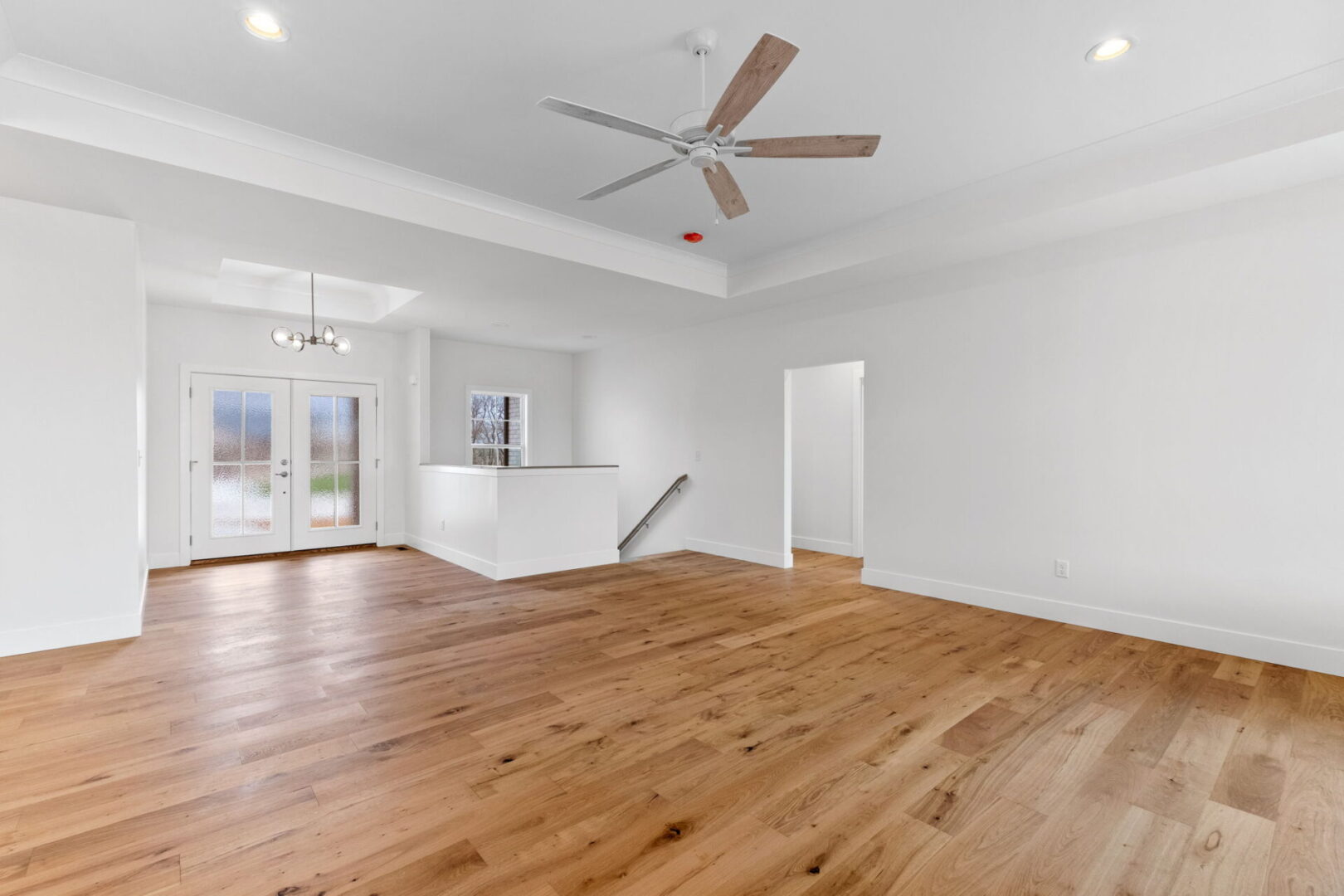 The kitchen showcases a contemporary design featuring custom Aspect cabinetry and quartz countertops, complemented by Café stainless steel appliances. It highlights a wooden bodice-shaped hood vent and modern dome lighting, all revolving around an impressive white oak island. In the great room, a tray ceiling and open staircase.