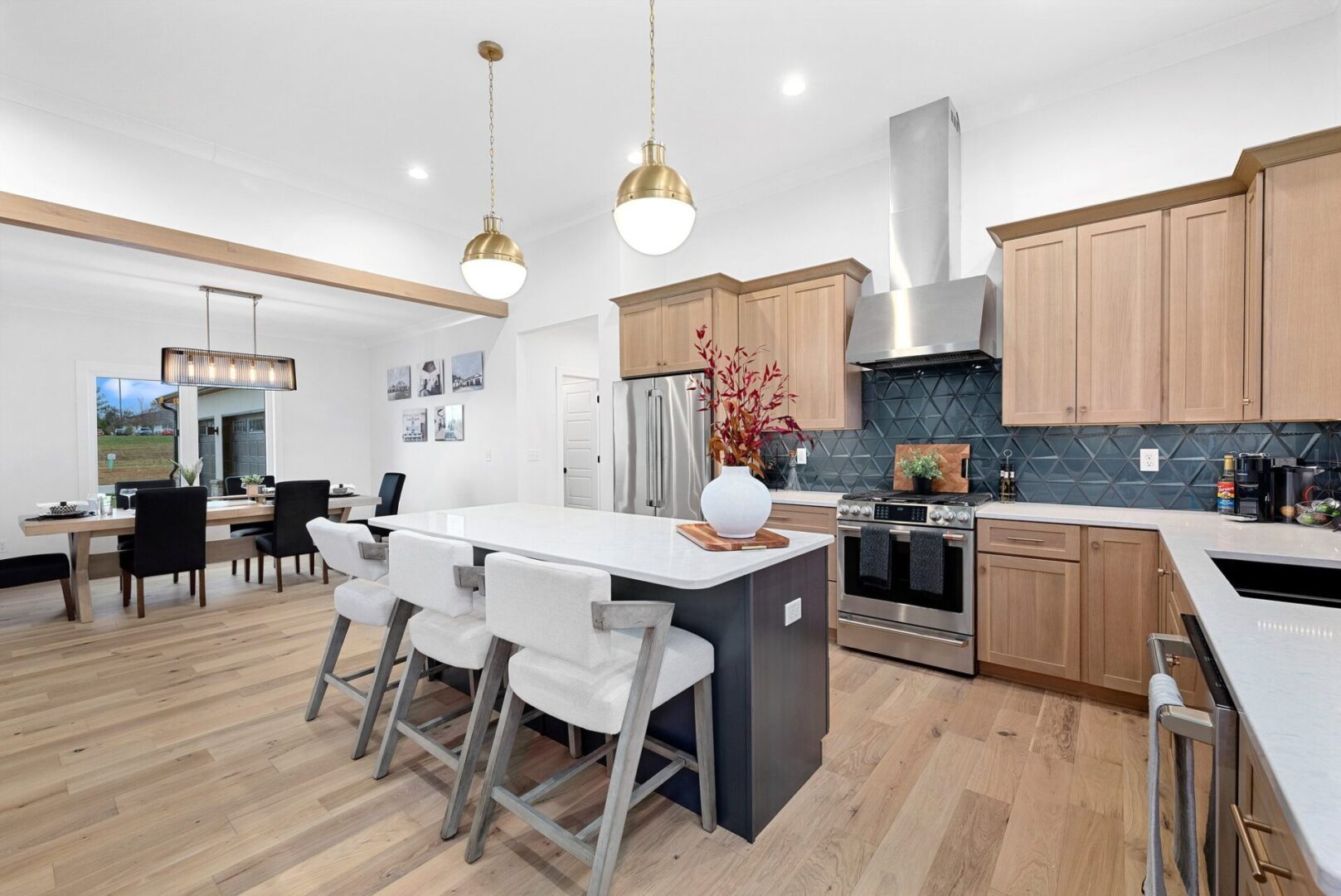 The kitchen boasts a modern design white oak with custom Shiloh cabinets and quartz countertops, paired with Cafe' stainless steel appliances. It features a bodice-shaped hood vent and contemporary dome lighting, all centered around a stunning navy hale island.