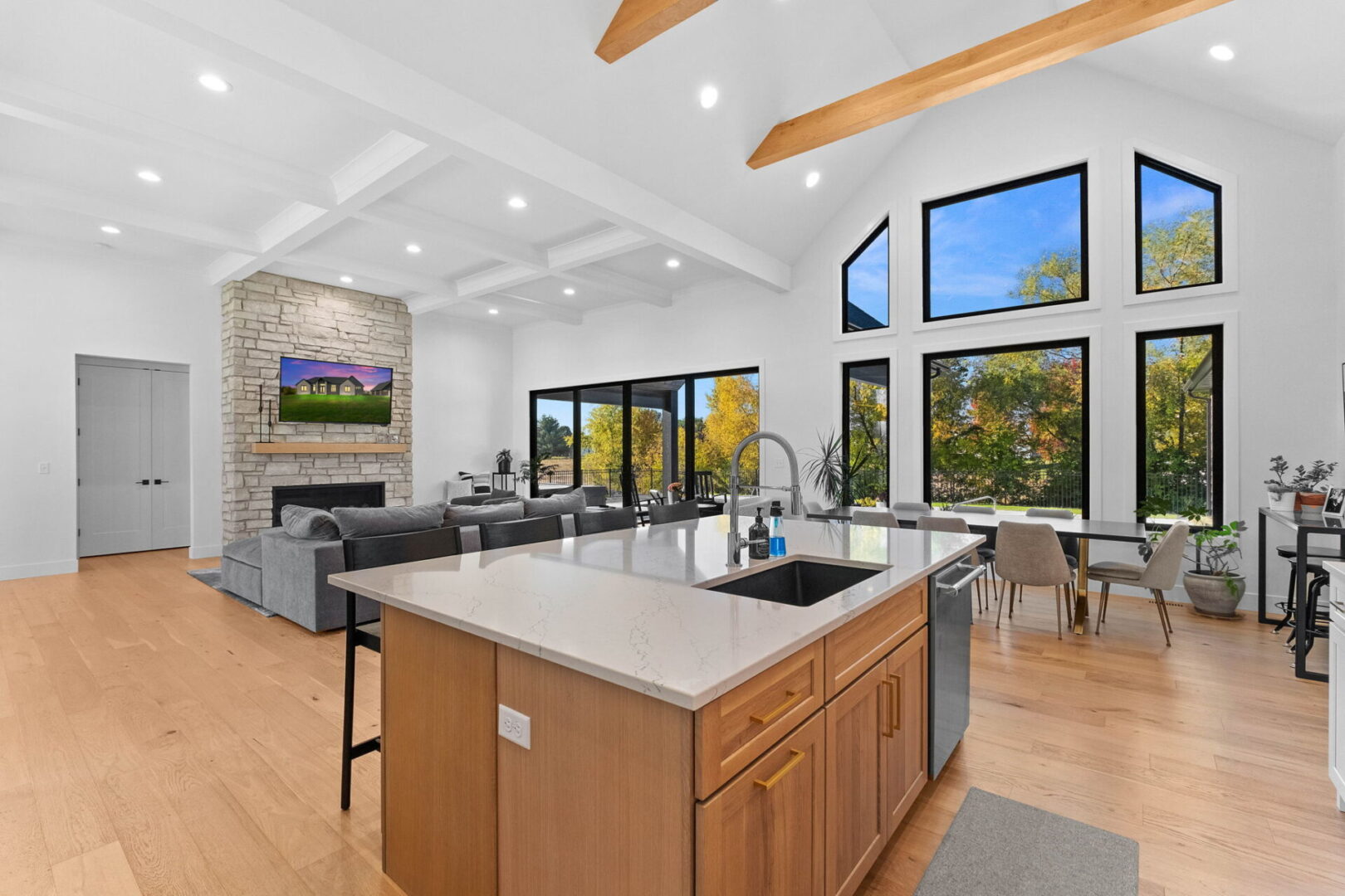 A great room with a coffered ceiling and a linear stone fireplace.