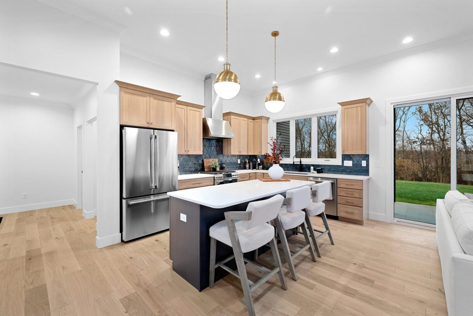 The kitchen boasts a modern design white oak with custom Shiloh cabinets and quartz countertops, paired with Cafe' stainless steel appliances. It features a bodice-shaped hood vent and contemporary dome lighting, all centered around a stunning navy hale island.
