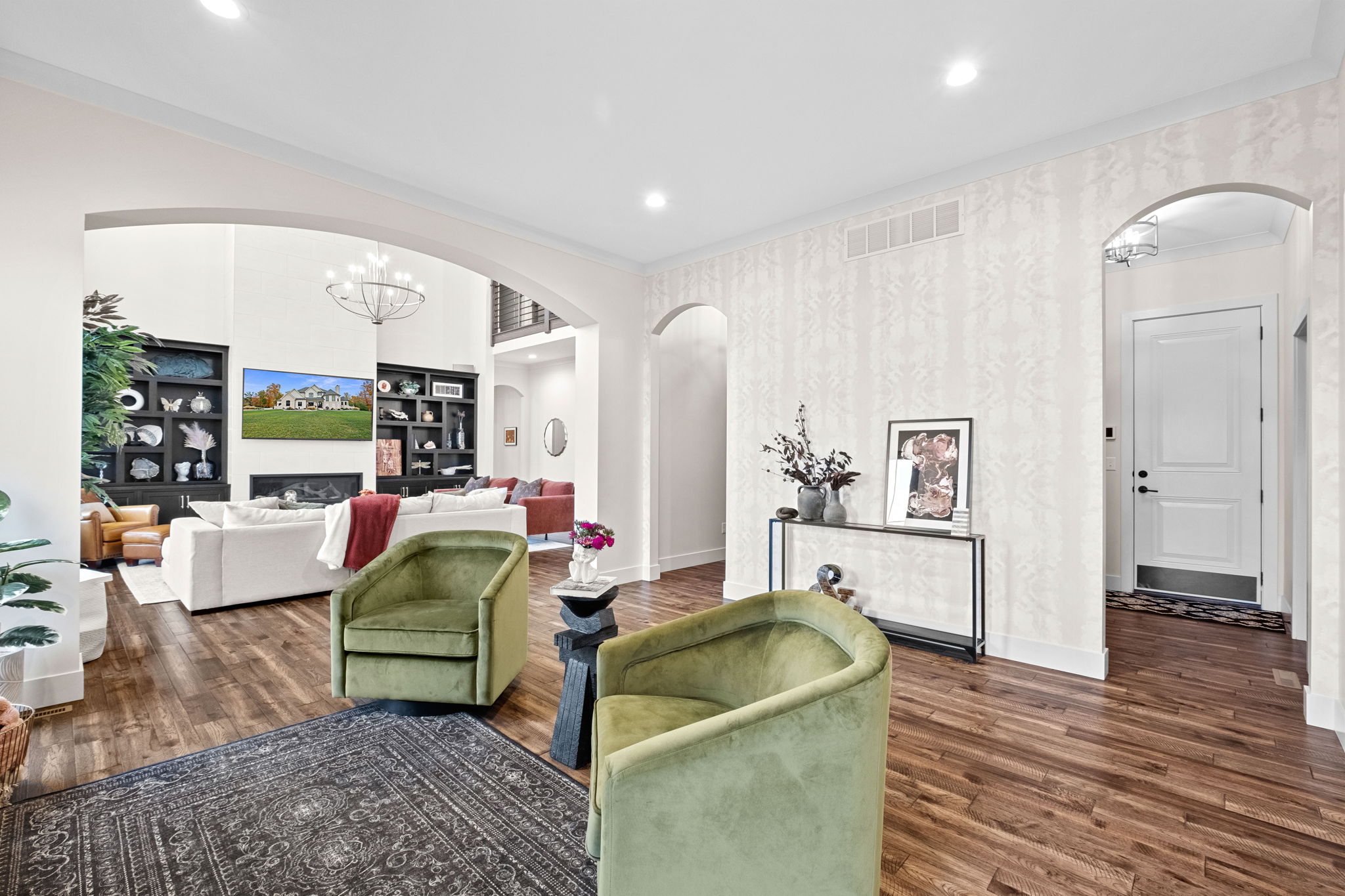 A sitting room adorned with custom wallpaper, featuring arched entryways and direct access to the butler's pantry and dining room.