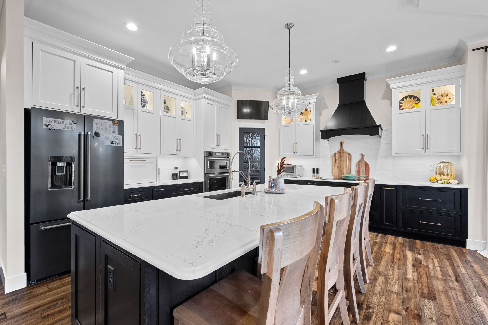 A modern kitchen featuring a large bay window, a drop ceiling, a spacious island with Cambria quartz countertops, and custom Shiloh cabinets.