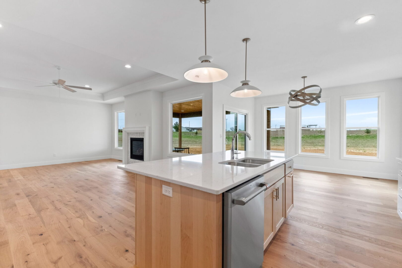 The kitchen showcases a contemporary design featuring custom Aspect cabinetry and quartz countertops, complemented by Café stainless steel appliances. It highlights a wooden bodice-shaped hood vent and modern dome lighting, all revolving around an impressive white oak island. The