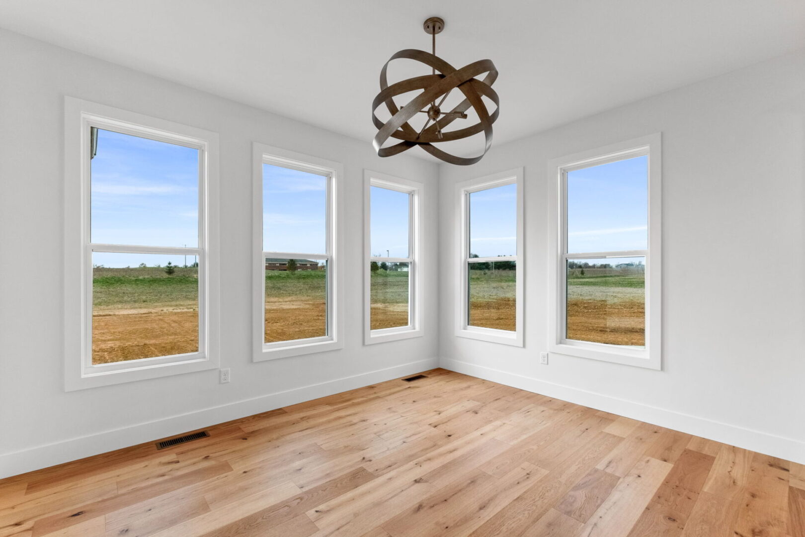 The dining room is bathed in bright natural light, complemented by a modern chandelier and engineered hardwood floors.