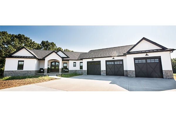 A modern farmhouse design featuring white brick and stone wainscoting, complemented by a ranch-style floor plan. Pioneer Ridge