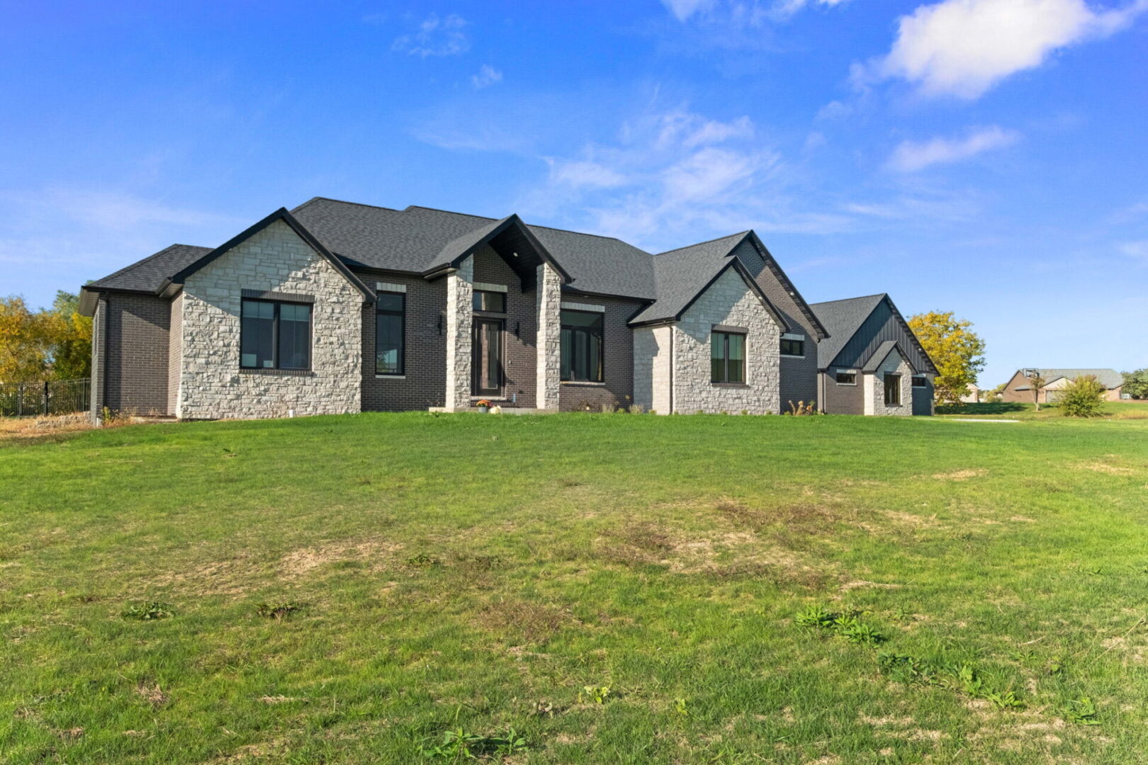 A contemporary-style home featuring black brick and stone, complete with an additional detached garage.