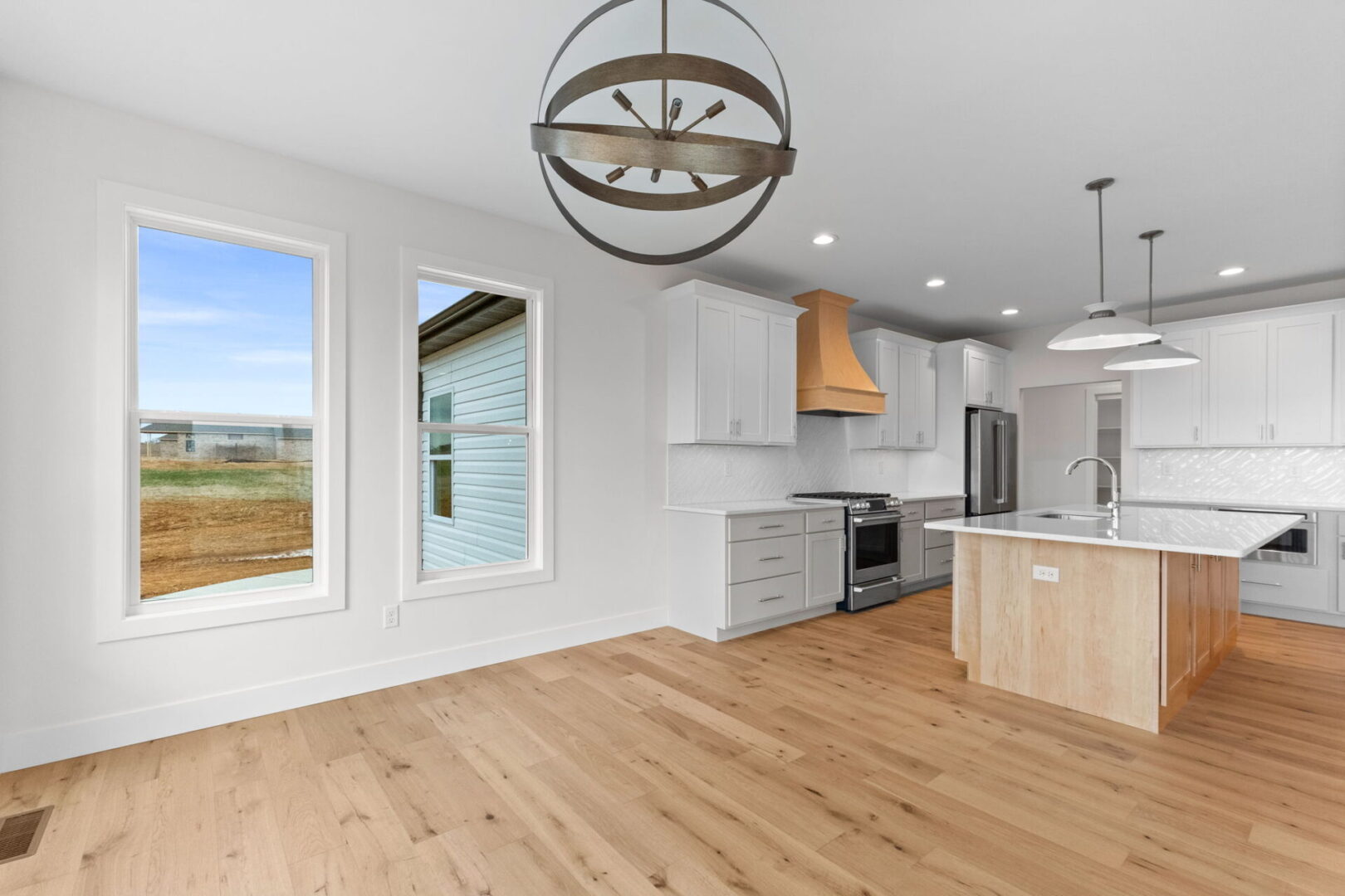 The kitchen showcases a contemporary design featuring custom Aspect cabinetry and quartz countertops, complemented by Café stainless steel appliances. It highlights a wooden bodice-shaped hood vent and modern dome lighting, all revolving around an impressive white oak island.The white diagonal picket tile backsplash adds a modern elegance to this contemporary and clean kitchen.