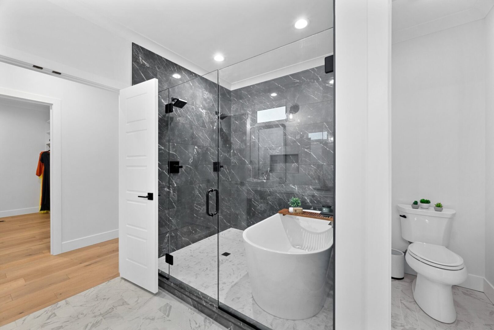 A primary bathroom designed as a wet room, featuring a shower and a freestanding tub, all enclosed by elegant glass.