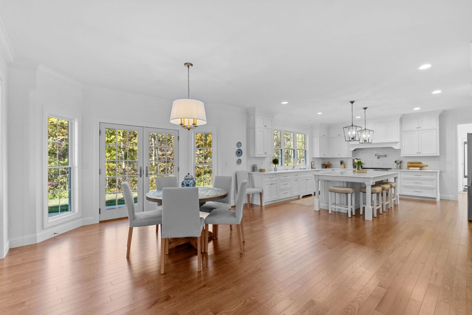 A luxurious, traditional colonial-style kitchen with an eat-in area and a modern open floor plan that extends through the kitchen into the great room.