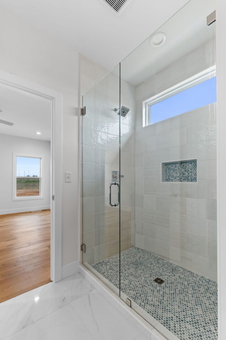 A primary bathroom featuring a walk-in shower with custom penny tile floor and modern off white 5x5 squares.