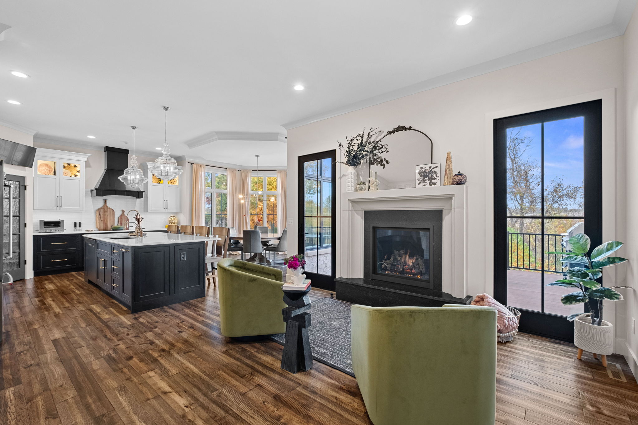 The sitting room, adjacent to the modern kitchen, boasts a large bay window, a drop ceiling, and a spacious island adorned with Cambria quartz countertops, complemented by custom Shiloh cabinets. An extravagant cast marble fireplace serves as the room's centerpiece.