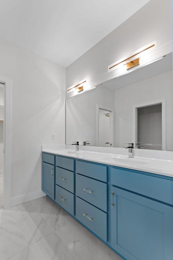 Primary bathroom with powder blue custom cabinets and modern lighting.
