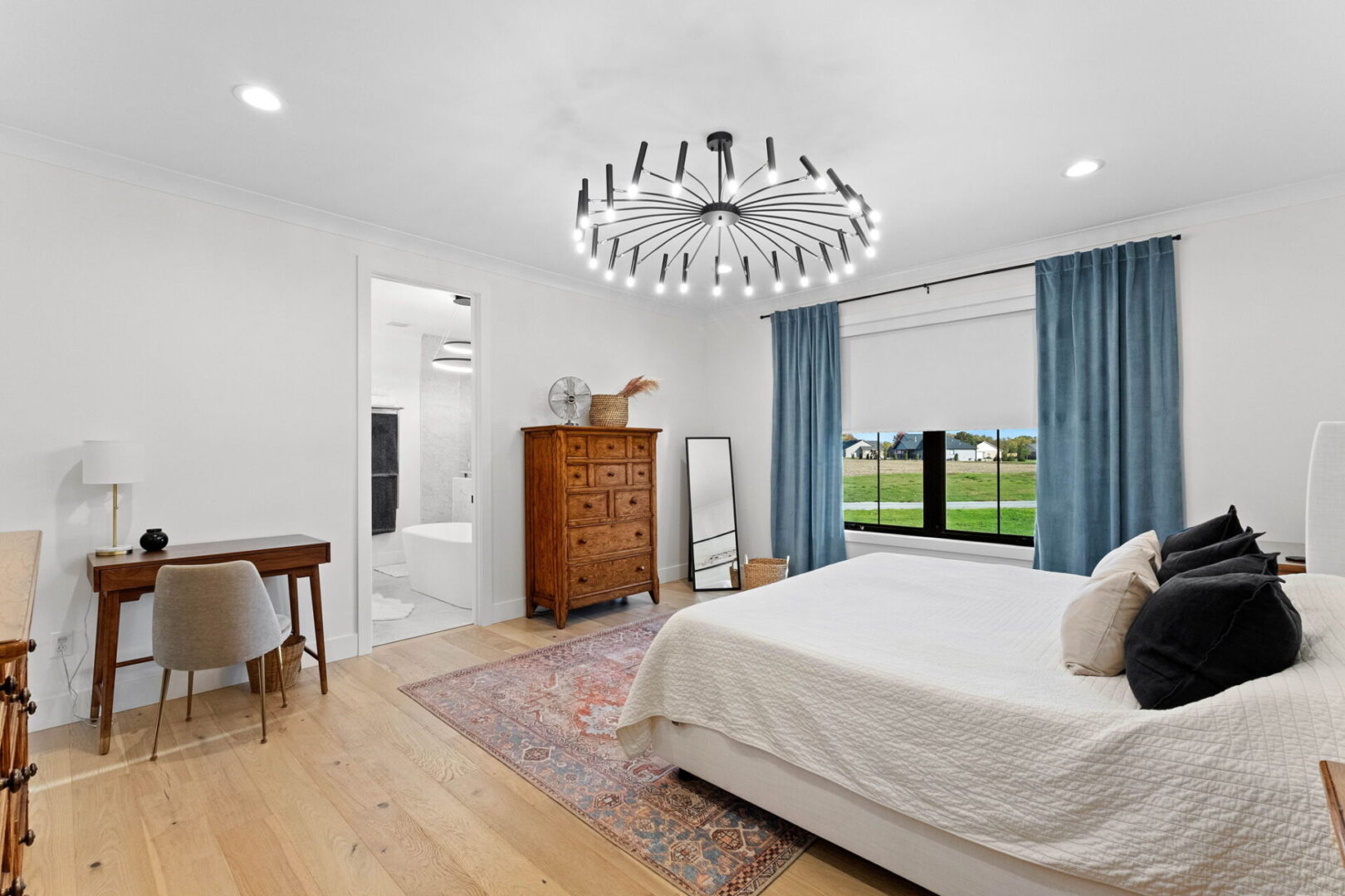 The primary bedroom featuring modern lighting and engineered hardwood flooring.