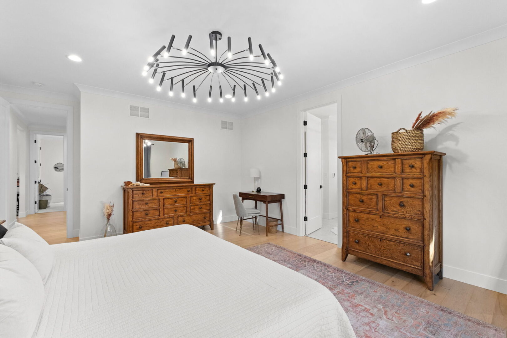 The primary bedroom featuring modern lighting and engineered hardwood flooring.