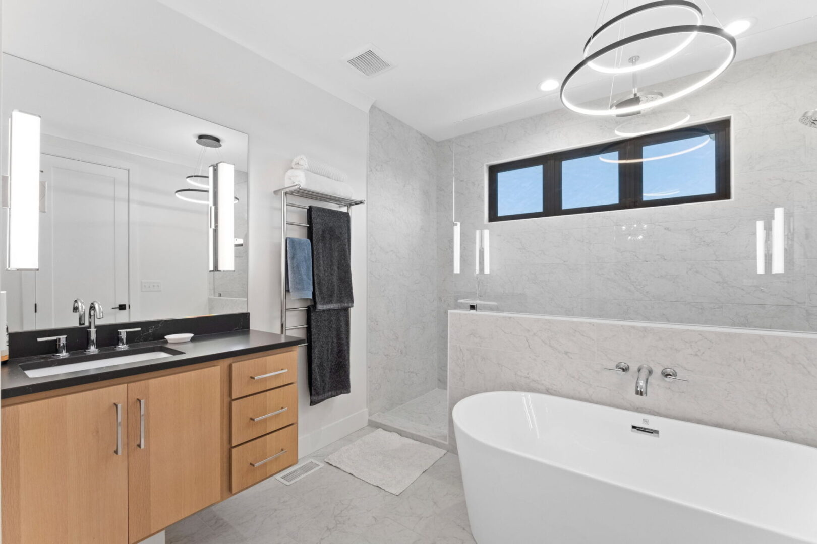 The Primary Suite bathroom boasts floating white oak vanities and a walk-in custom tile shower, soaking tub all complemented by easy access to a spacious walk-in closet.