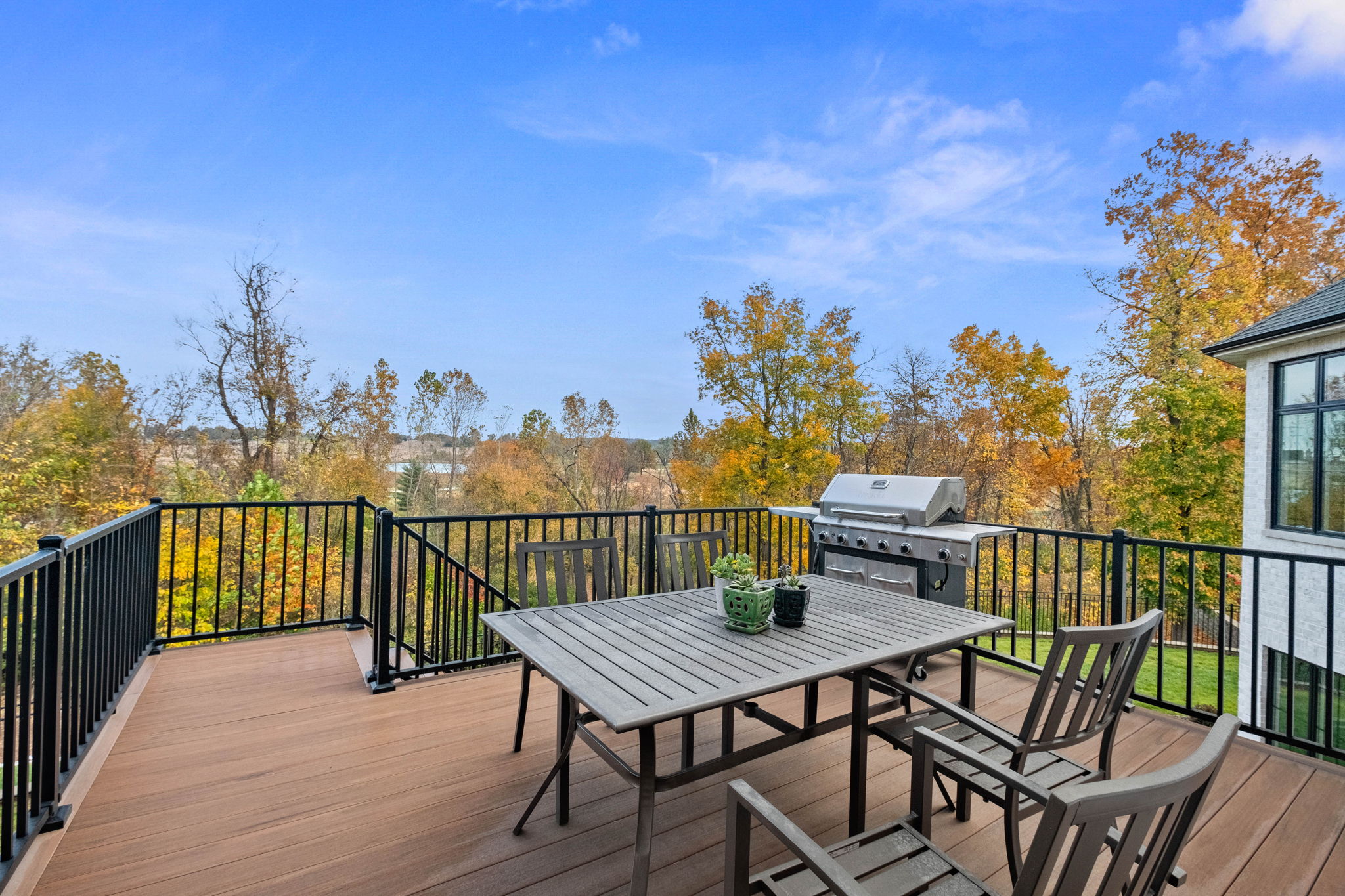 The deck is situated adjacent to the sitting room and kitchen, with stairs descending to the backyard and the hot tub.
