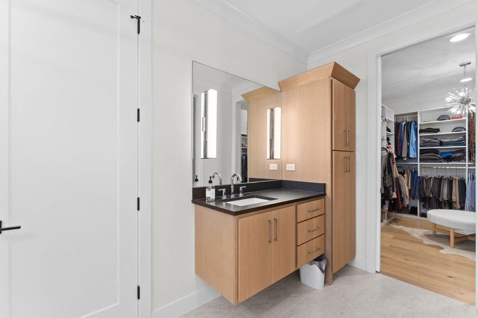 The Primary Suite bathroom boasts floating white oak vanities and a walk-in custom tile shower, complemented by easy access to a spacious walk-in closet.