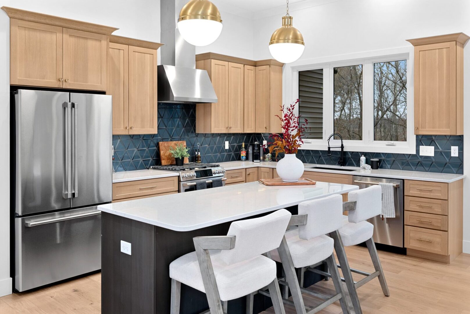 The kitchen boasts a modern design white oak with custom Shiloh cabinets and quartz countertops, paired with Cafe' stainless steel appliances. It features a bodice-shaped hood vent and contemporary dome lighting, all centered around a stunning navy hale island.