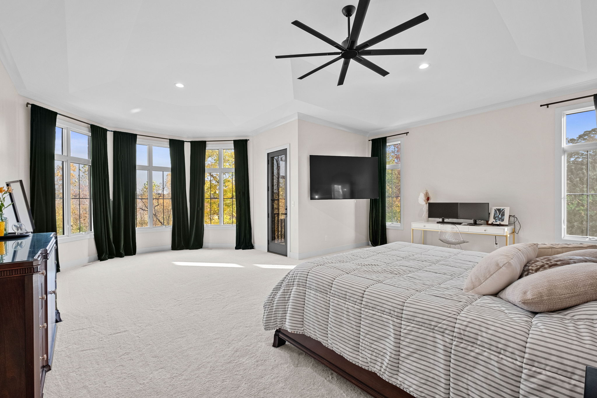 A primary suite featuring soaring ceilings over 10 feet high and a secluded balcony.