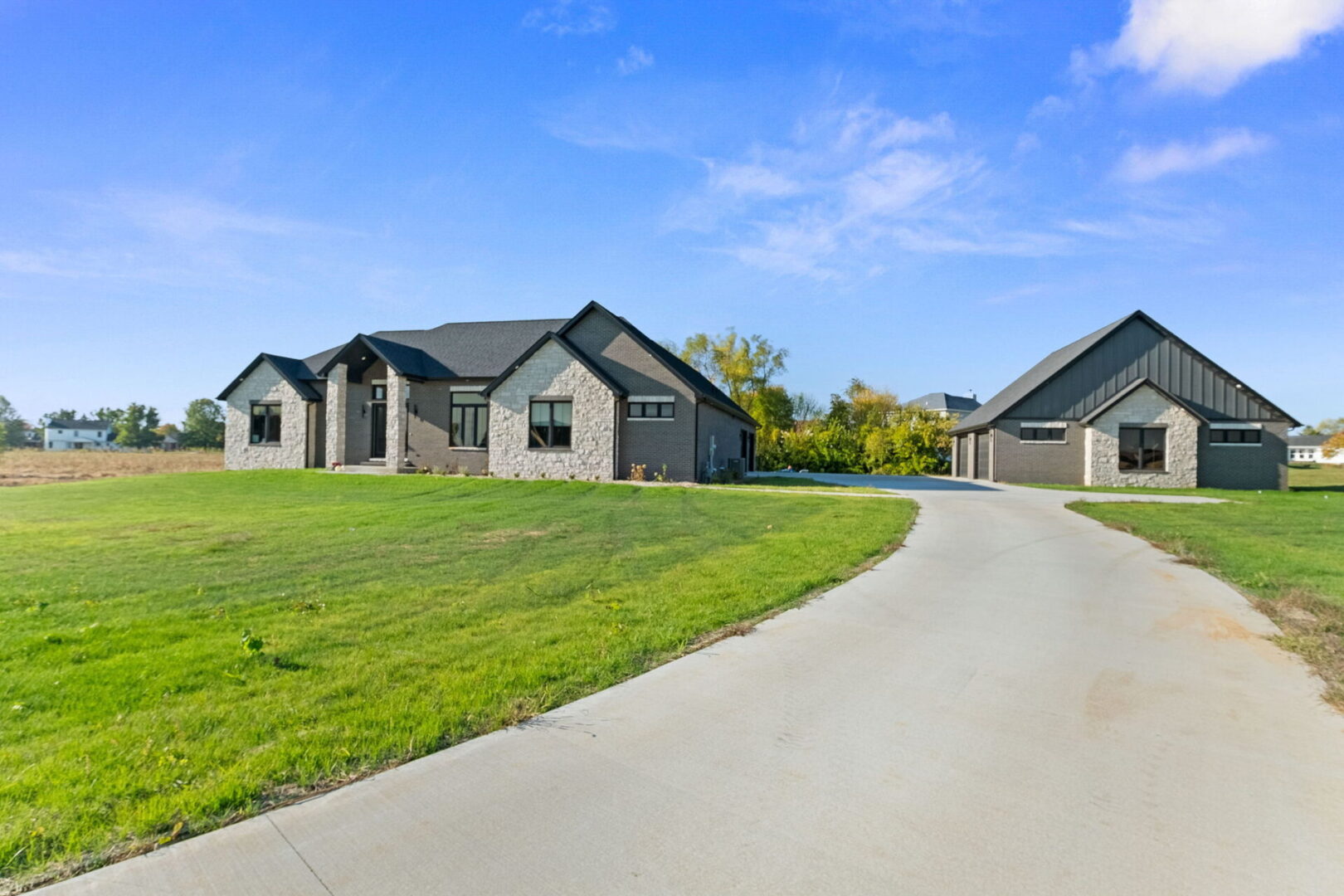 A contemporary-style home featuring black brick and stone, complete with an additional detached garage.