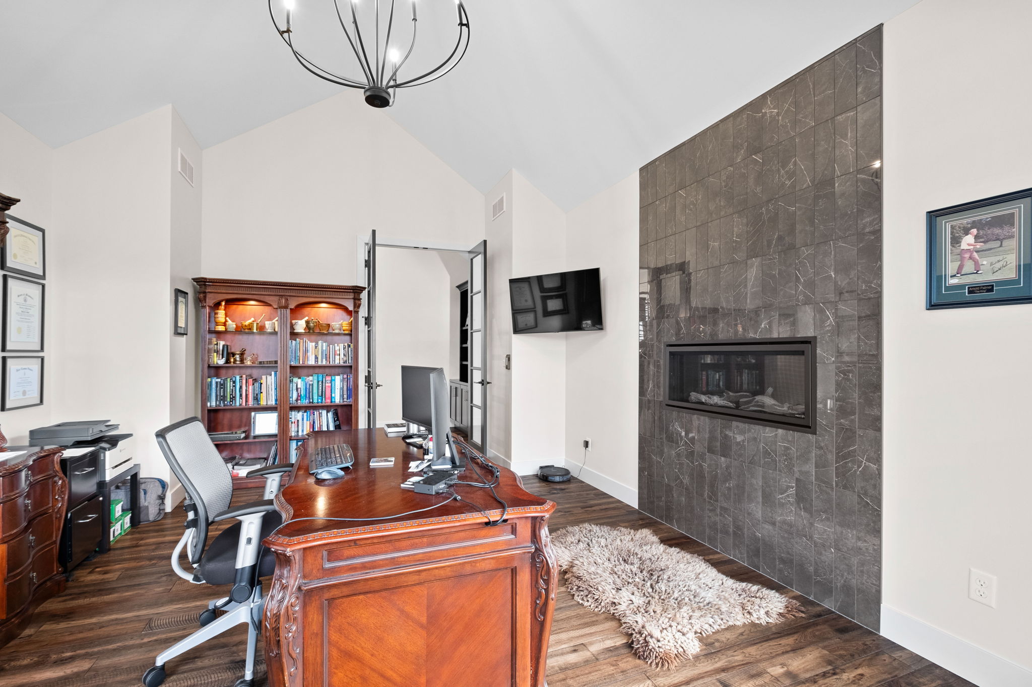 An upstairs office featuring a large, tiled fireplace and French doors.