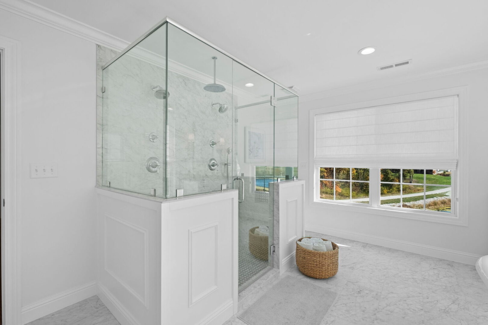 A Colonial-style home boasts a classically elegant primary bathroom, complete with pristine white and marble finishes. It features double separate vanities and a spacious walk-in shower.