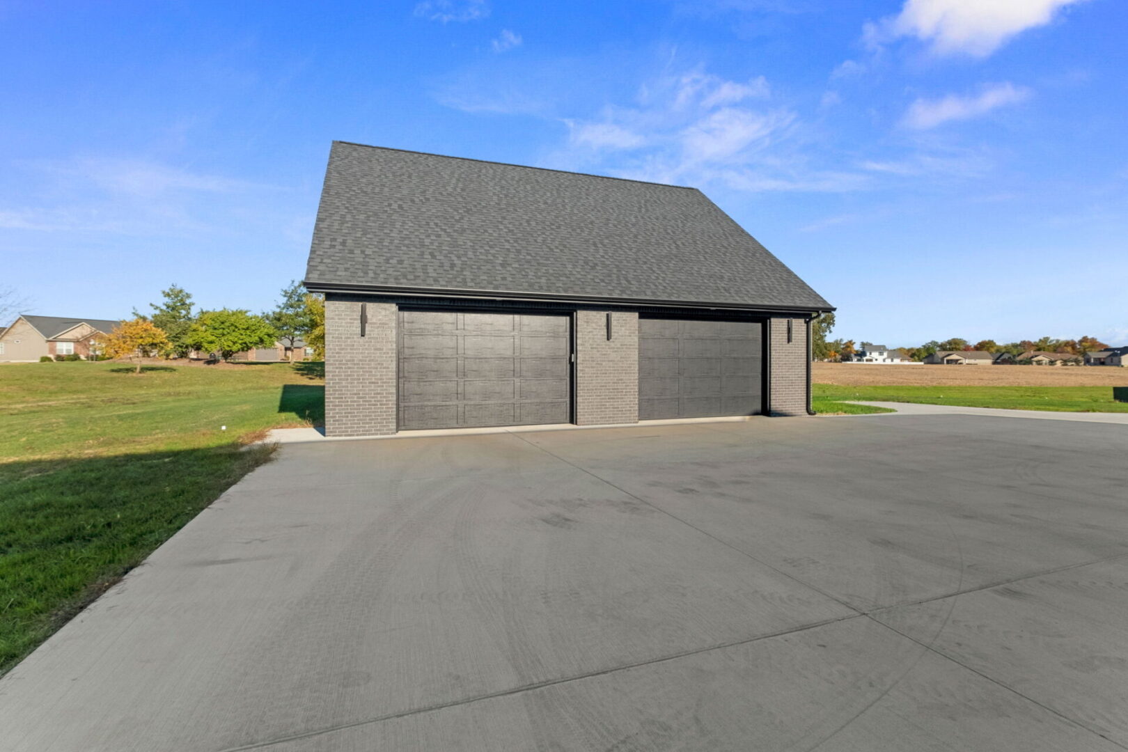 A contemporary-style home featuring black brick and stone, complete with an additional detached garage.