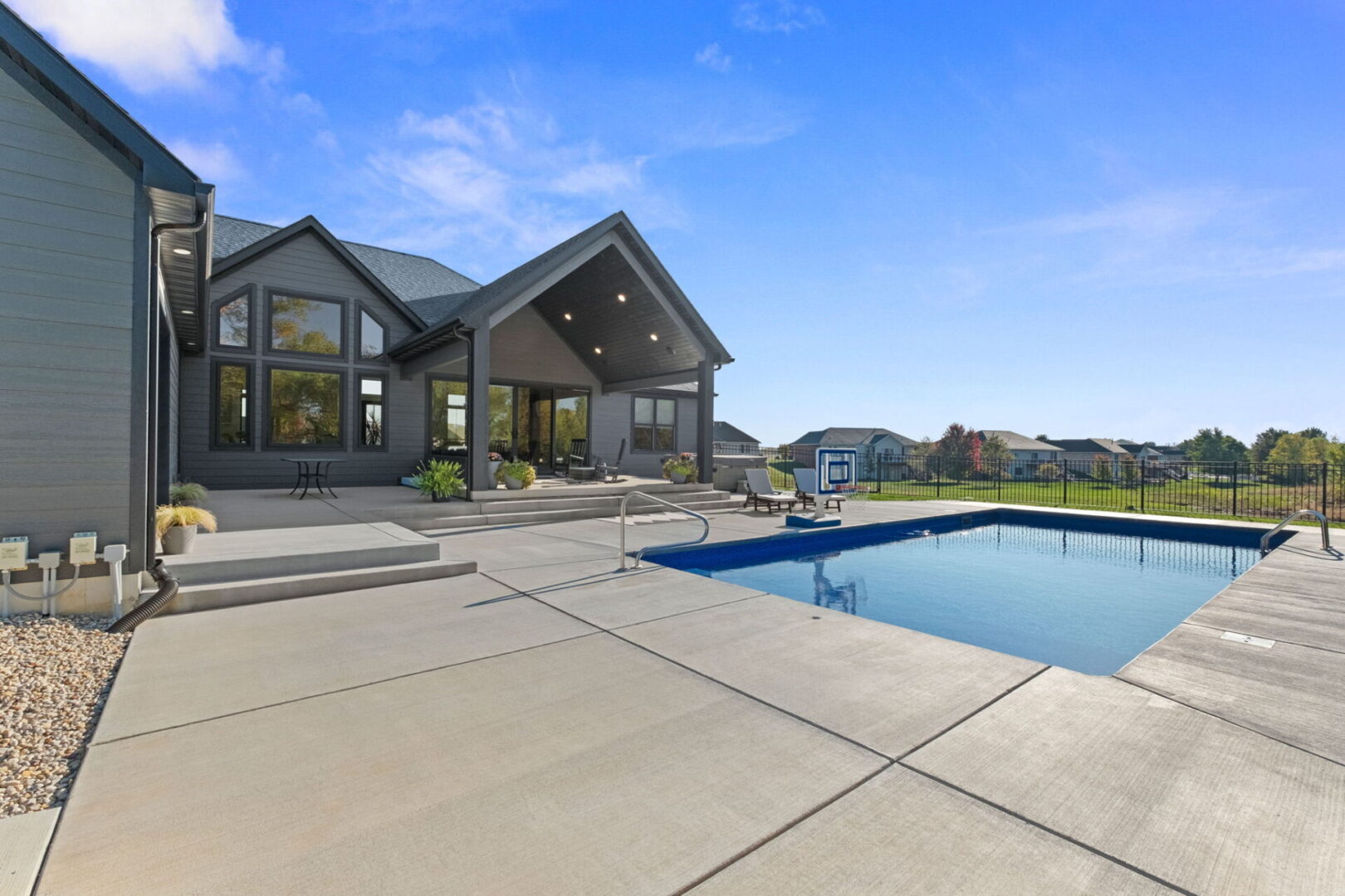 A rear view showcases the contemporary modern home, complete with a spacious fenced-in pool area and an expansive covered deck.