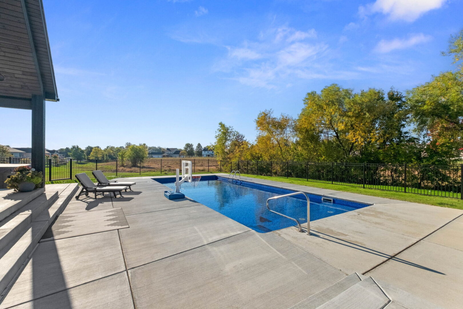A rear view showcases the contemporary modern home, complete with a spacious fenced-in pool area and an expansive covered deck.