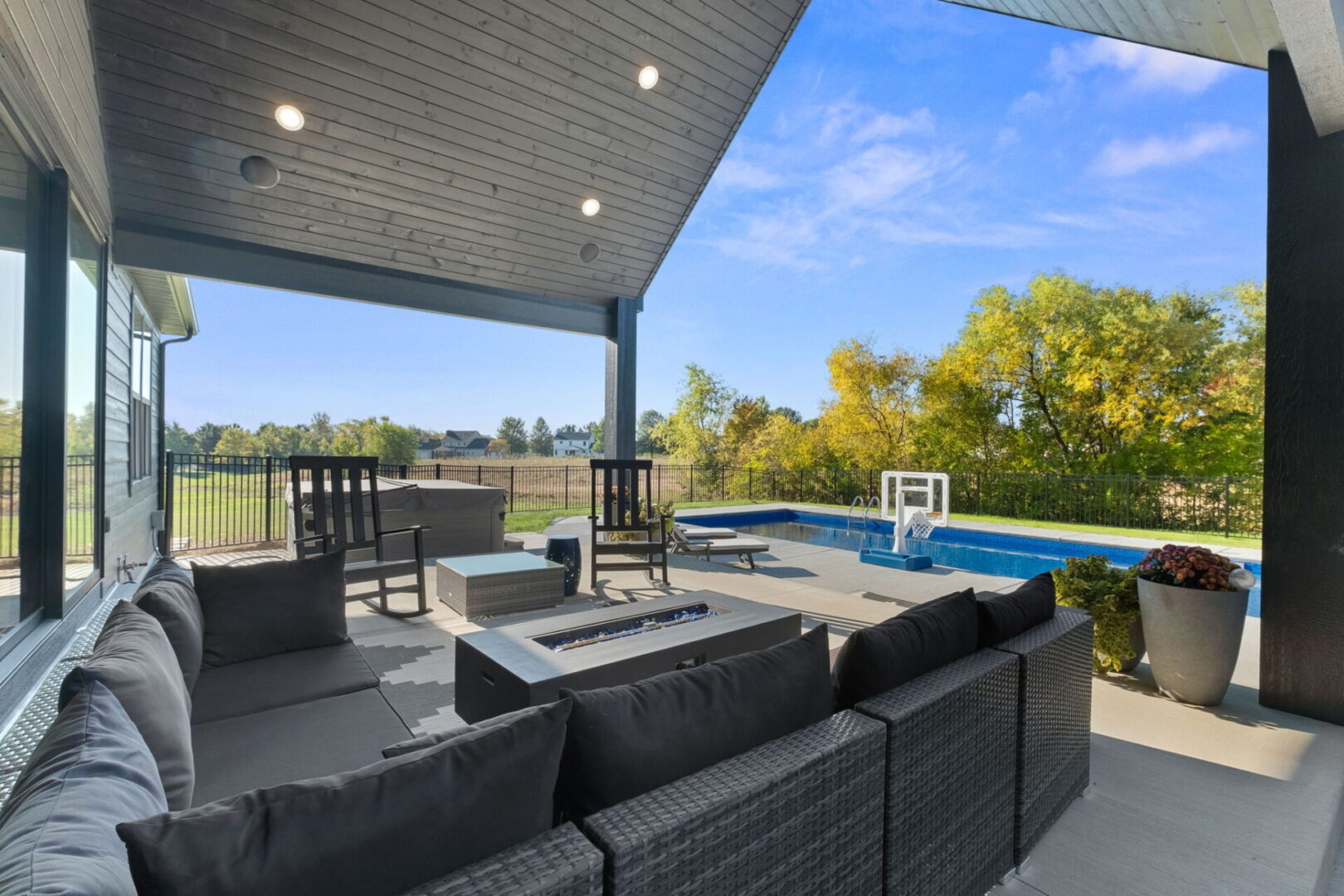This contemporary modern home features a spacious, fenced-in pool area and an expansive covered deck, perfect for entertaining.