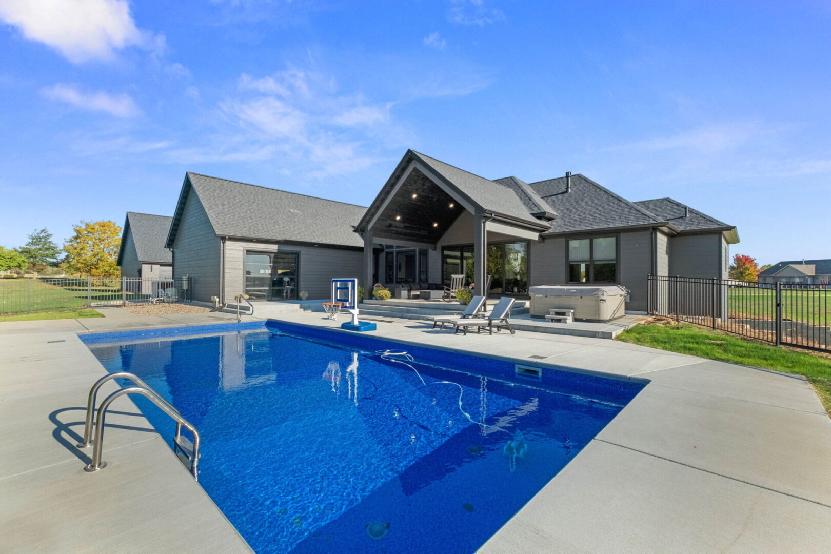 A rear view showcases the contemporary modern home, complete with a spacious fenced-in pool area and an expansive covered deck.