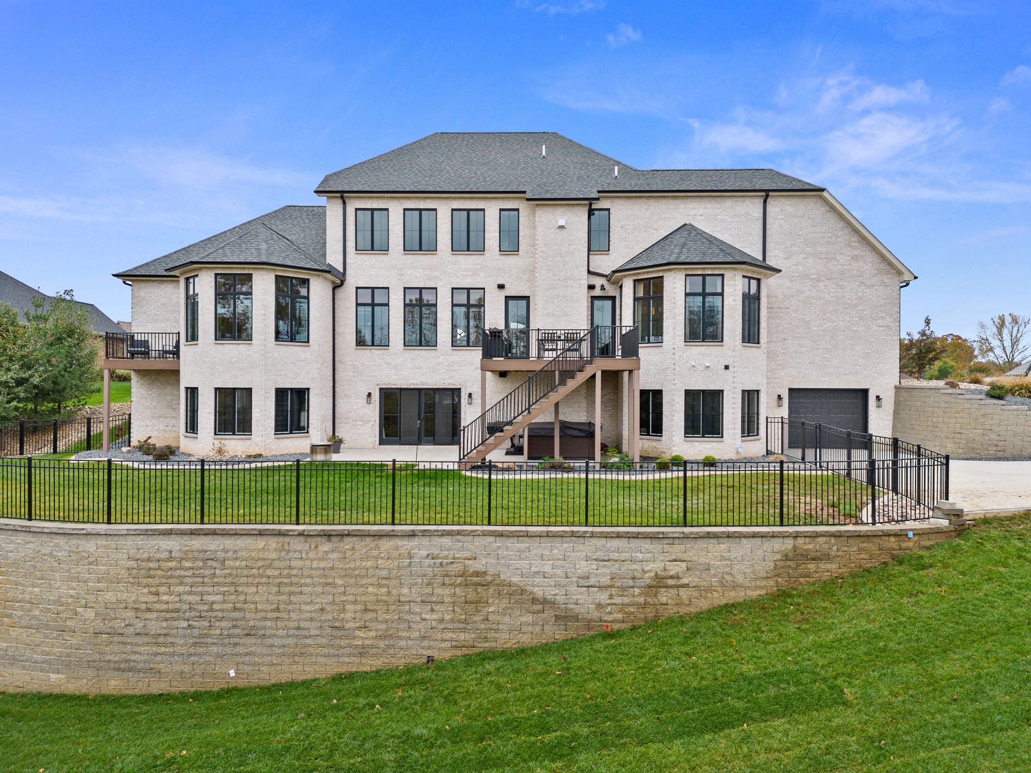 The home features a rear view of the European style, complete with stone and EIFS. It boasts large back decks accessible from the kitchen and a private deck adjoining the primary bedroom suite.