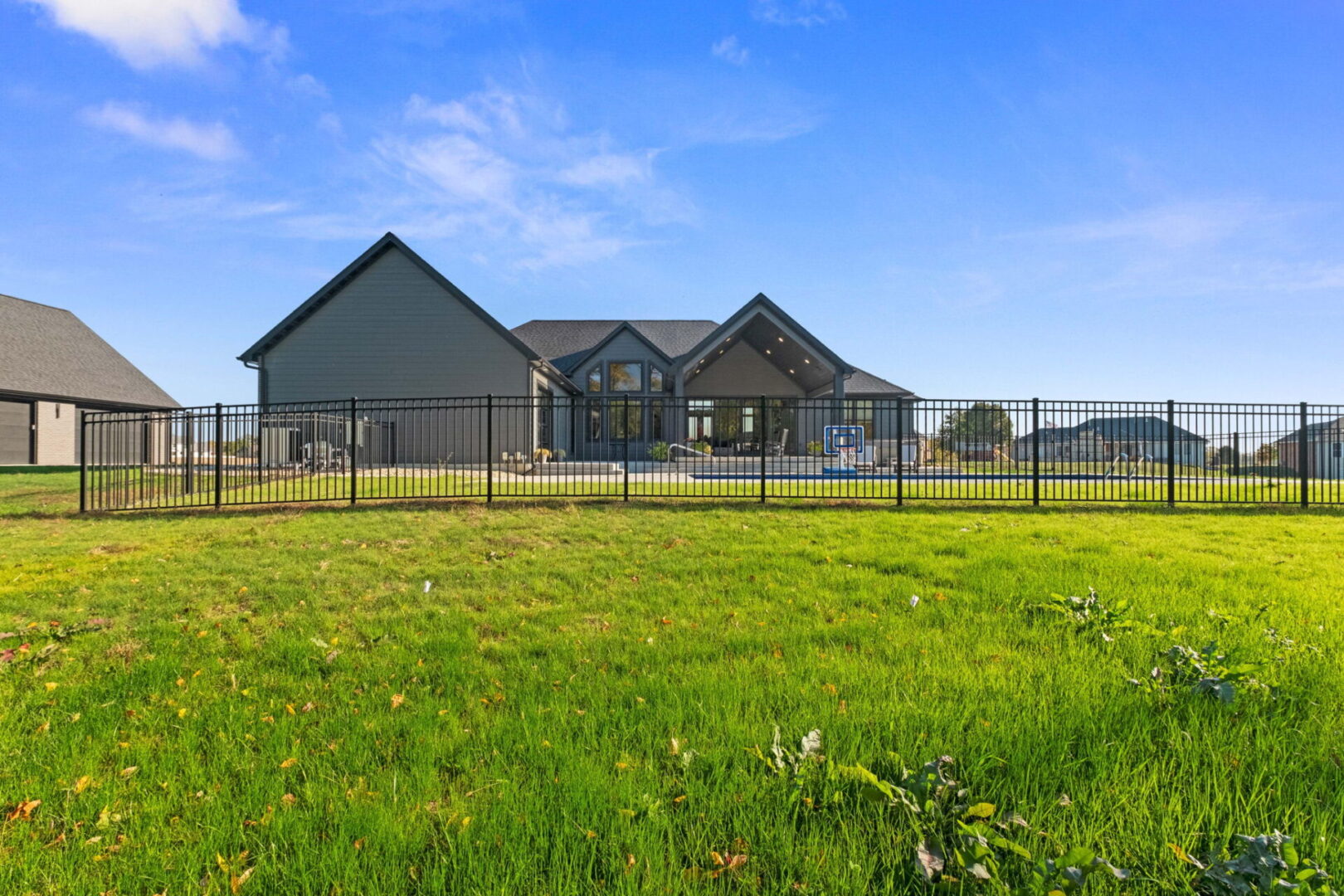 A rear view showcases the contemporary modern home, complete with a spacious fenced-in pool area and an expansive covered deck.