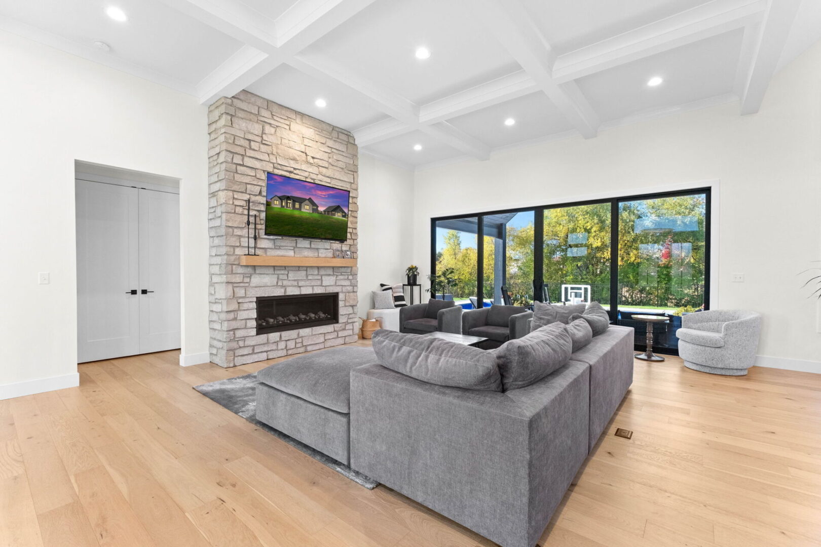 A great room with a coffered ceiling and a linear stone fireplace.
