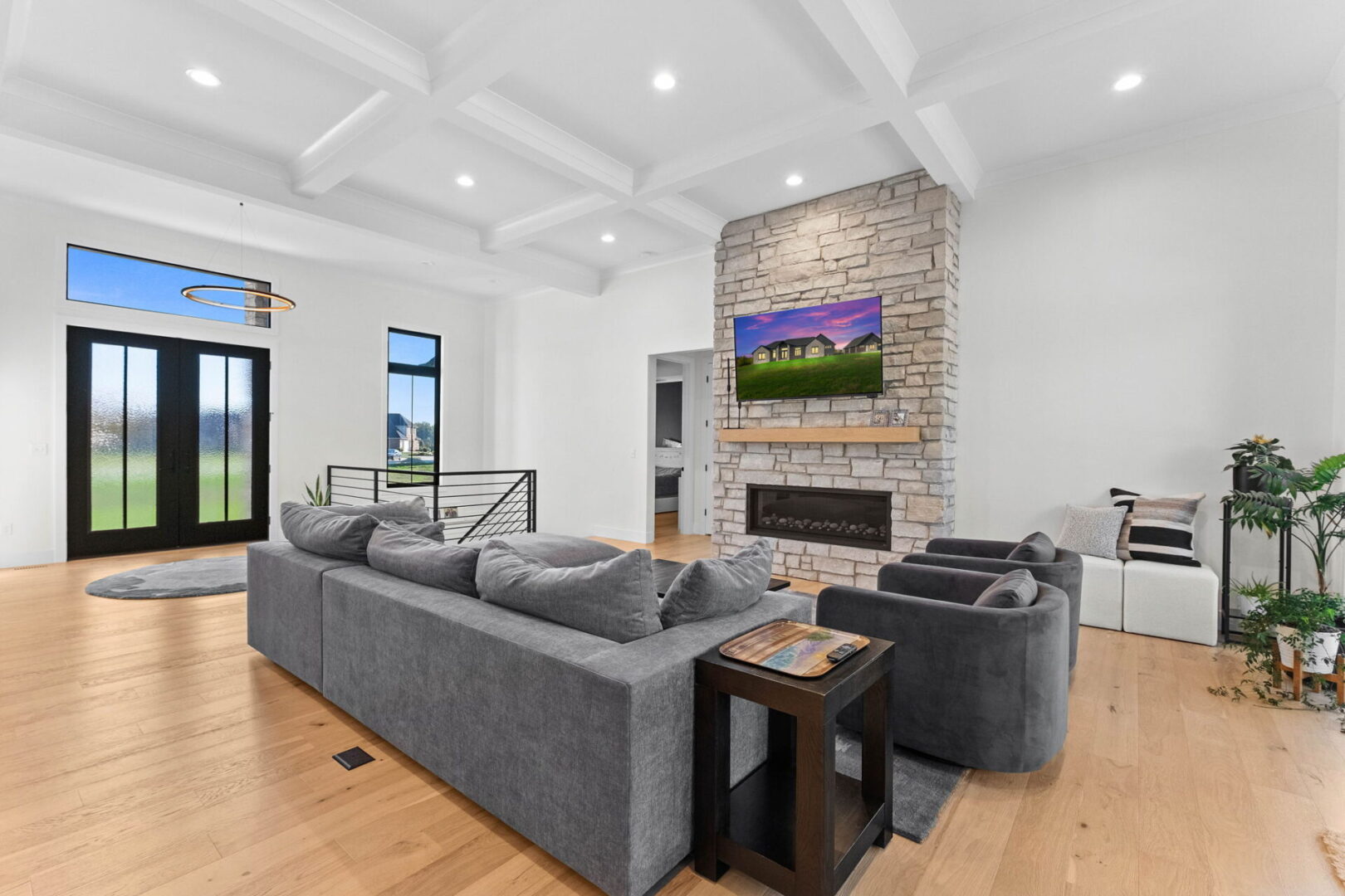 A great room with a coffered ceiling and a linear stone fireplace.