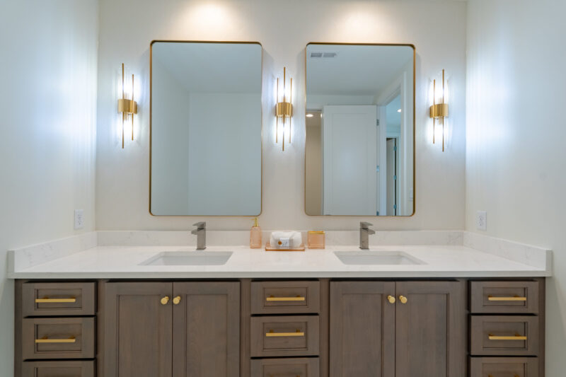 Bathroom has a floating vanity with double bowl sinks and stained cabinets.