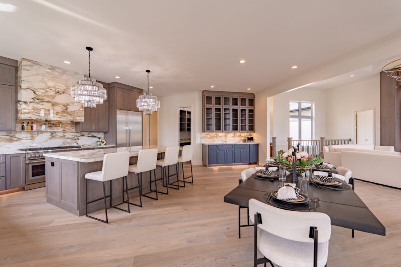 Luxurious large kitchen and dining room with custom stained cabinets and elegant countertops, with a two-toned bar.