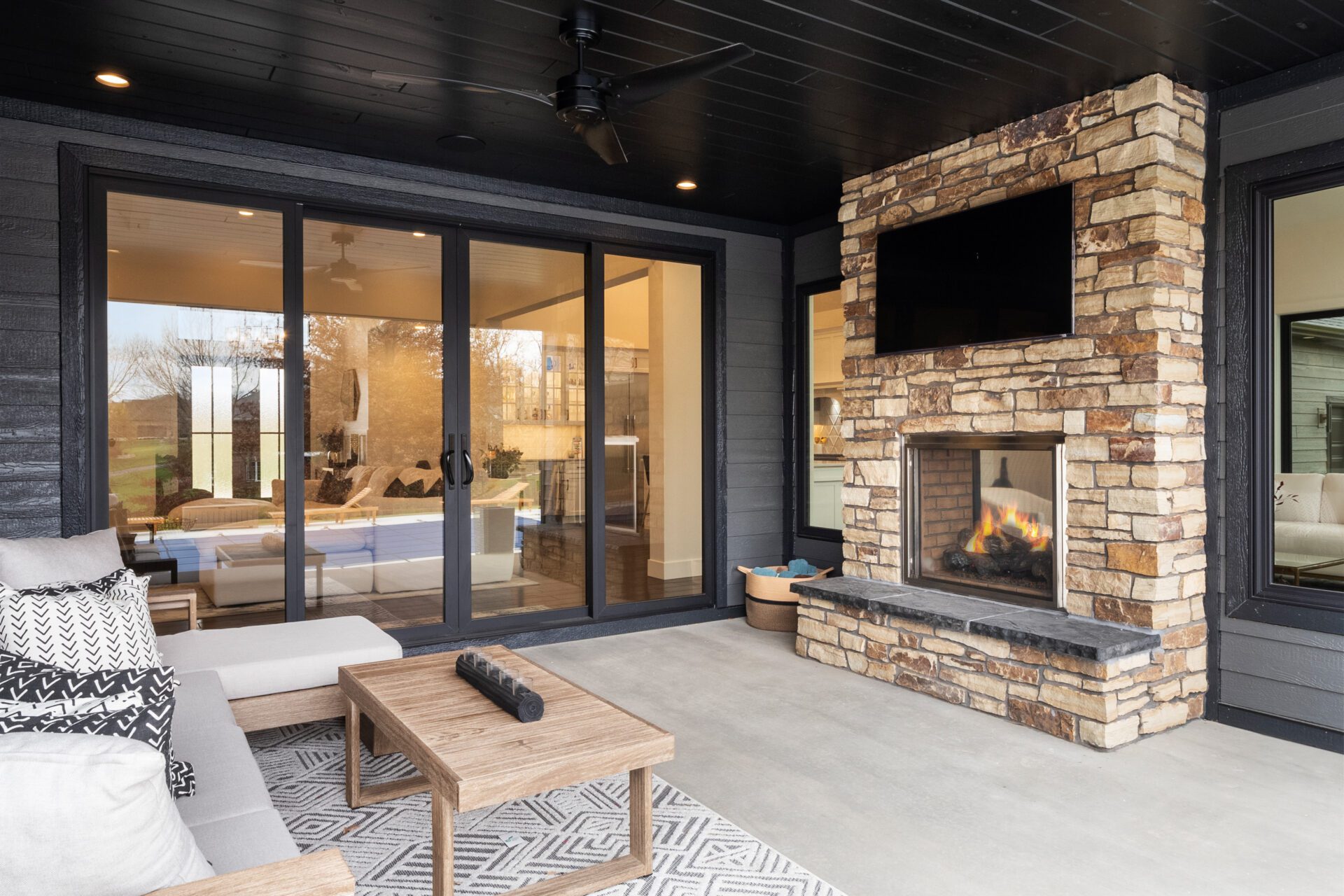 A contemporary, modern stone fireplace with a covered deck.