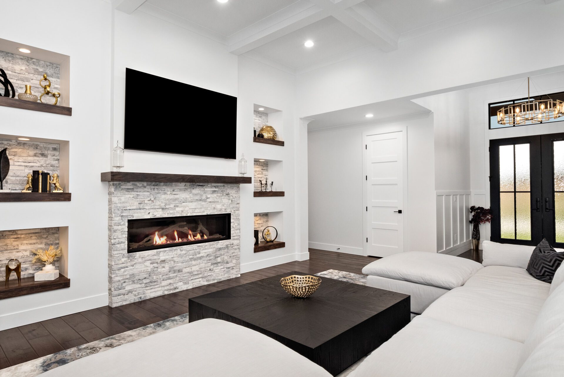 Envision a spacious, open-concept home with a contemporary modern design, boasting a coffered ceiling and wide sliding glass doors that open to a covered porch. It features elegant modern-style built-in niches and a substantial linear stone fireplace.