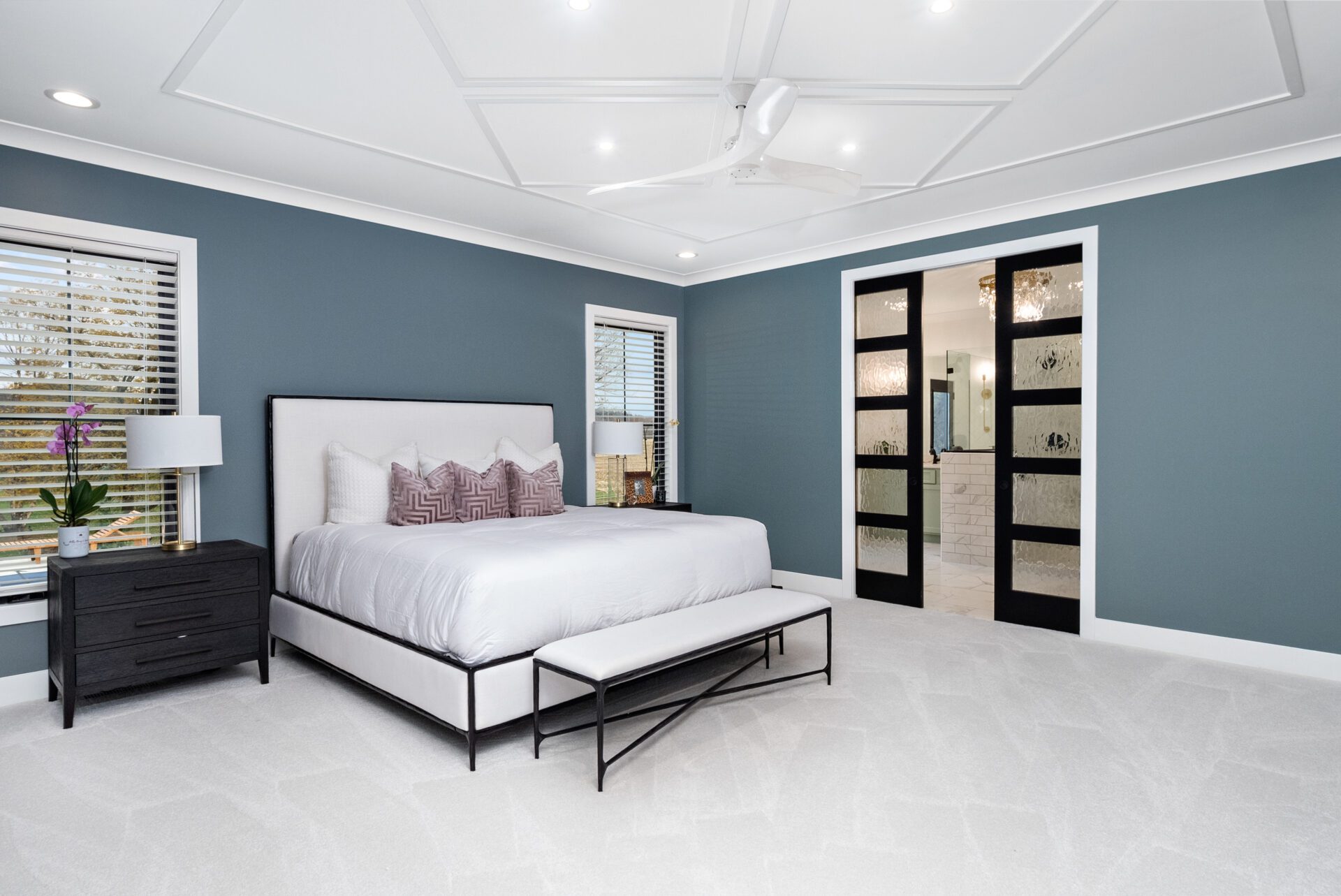 The primary bedroom suite boasts double glass doors leading into the bathroom.